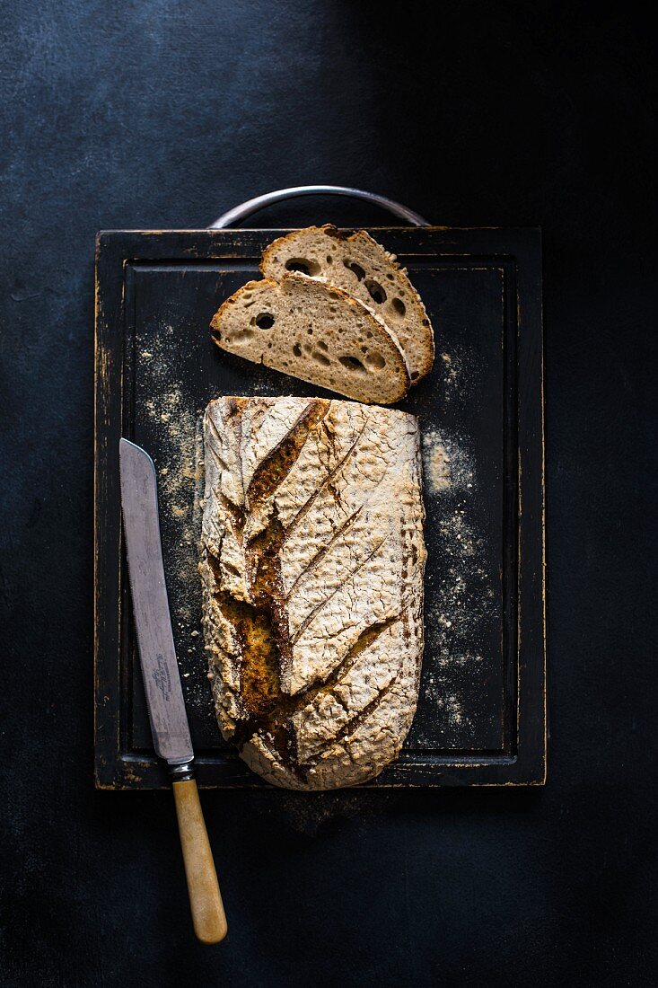 Freshly baked sourdough bread on a chopping board with a knife