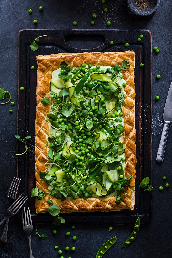 A puff pastry tart with cream cheese, peas, courgette and watercress salad