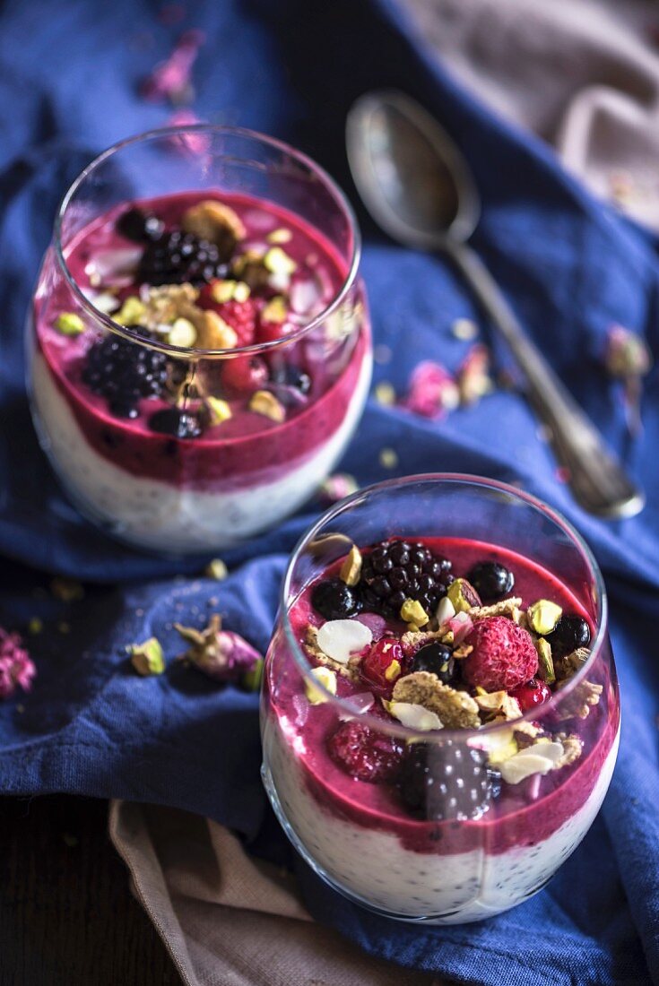 Chia pudding topped with cereal and a berry smoothie in a glass