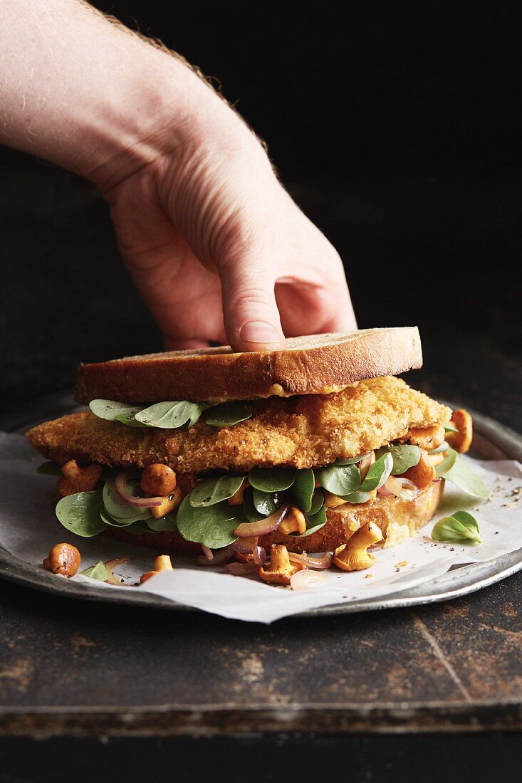 A potato bread sandwich with schnitzel, purslane and fresh chanterelle mushrooms