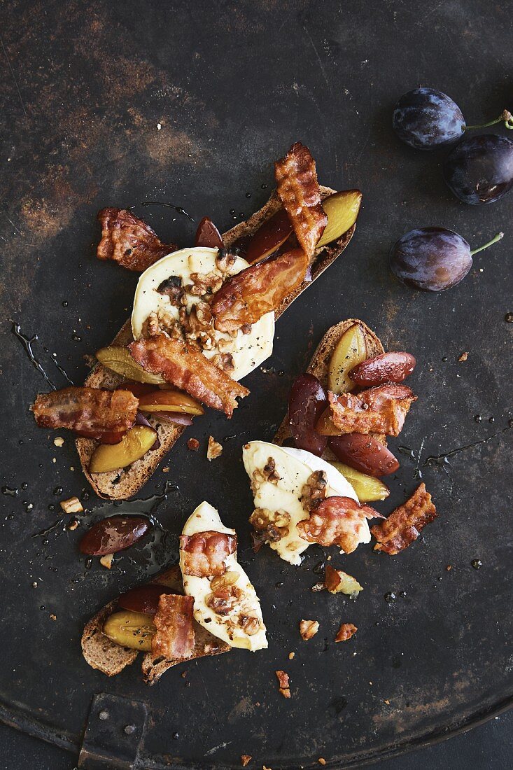An autumnal open sandwich with Camembert, plums, nuts and crispy bacon
