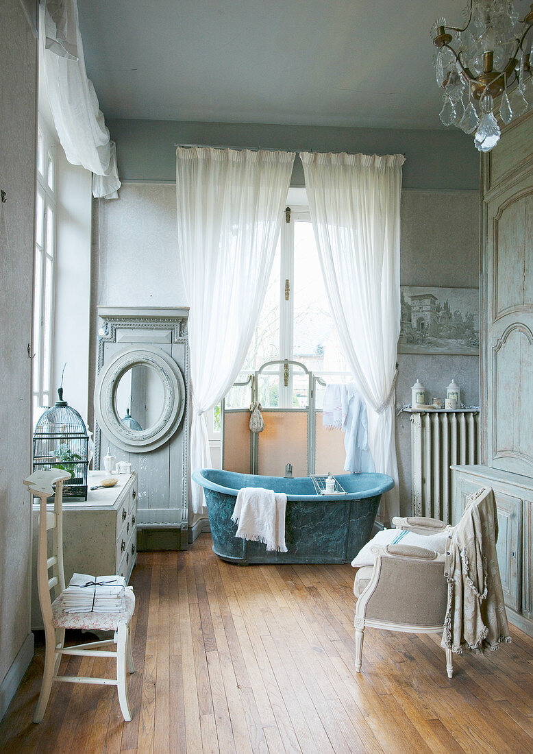 Free-standing bathtub in front of window in historical bathroom