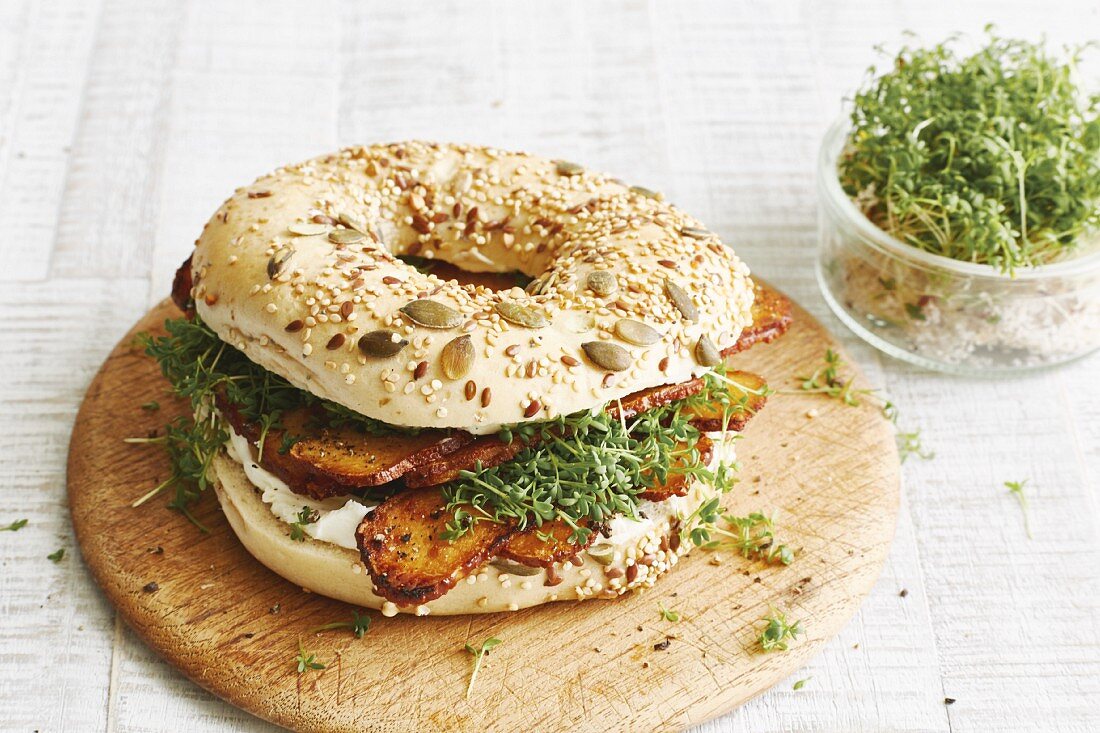 A bagel with crispy tofu, cream cheese and cress