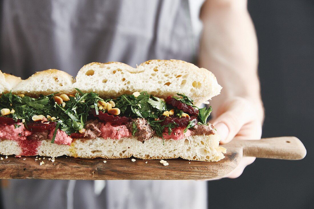 A flatbread sandwich with two different types of hummus, beetroot and parsley