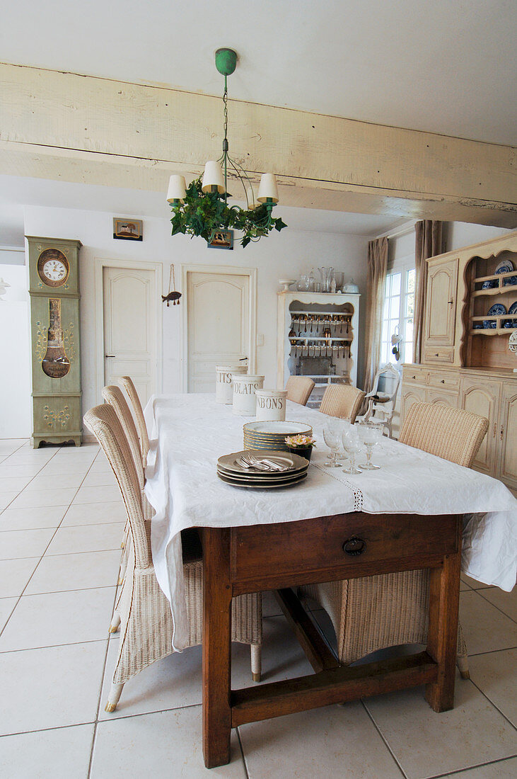 White tablecloth on long wooden table with wicker chairs