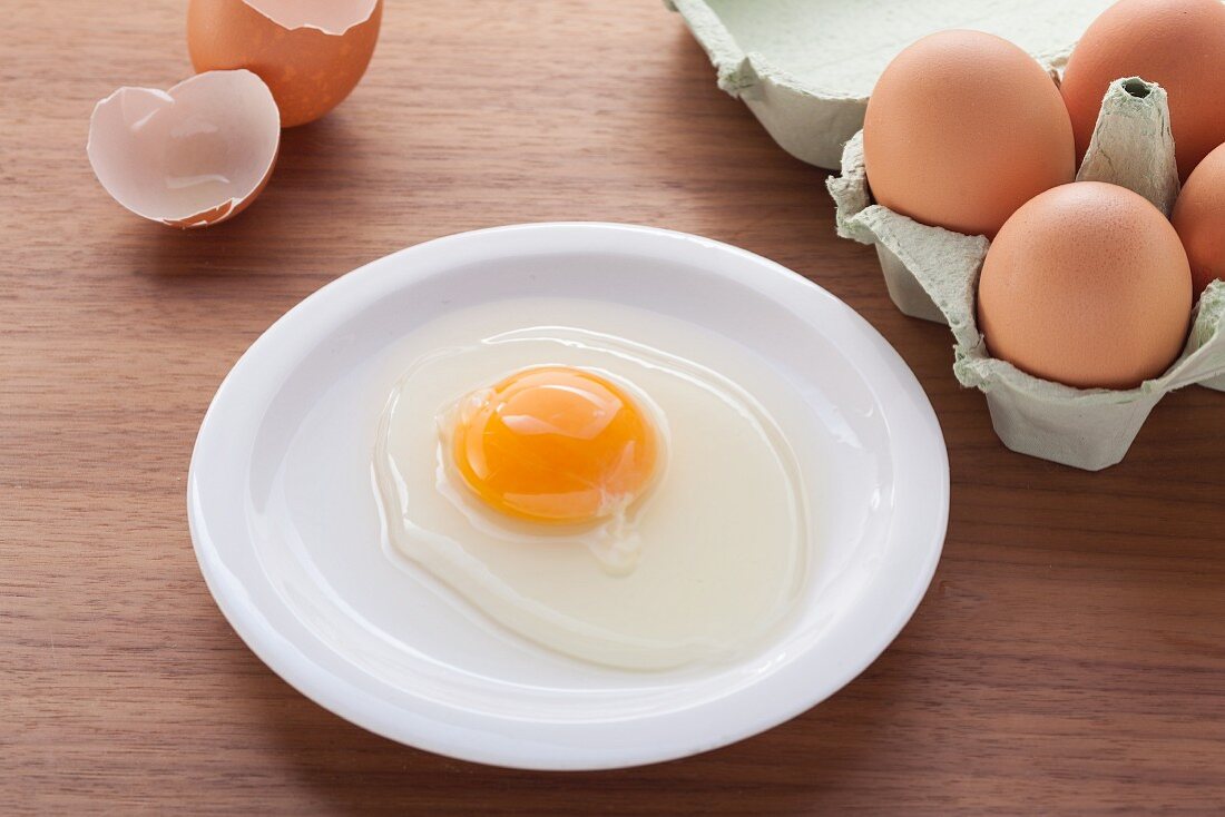 Frisch aufgeschlagenes Ei auf Teller
