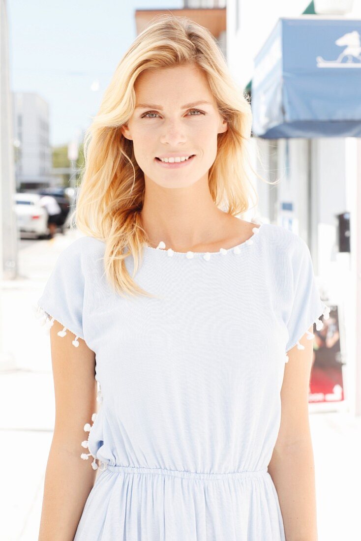 A blonde woman wearing a light blue dress with tassels