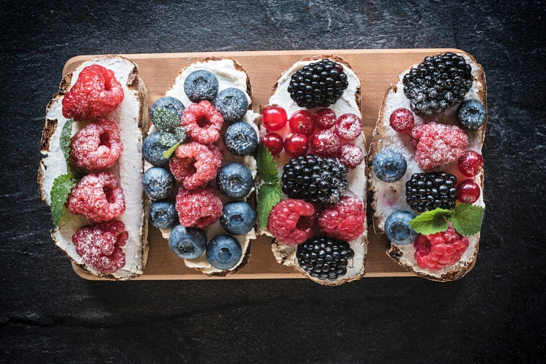 Bruschettas with berries and cream cheese on a wooden board