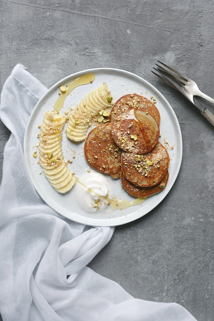 Banana pancakes with coconut yoghurt, pistachios and coconut flakes