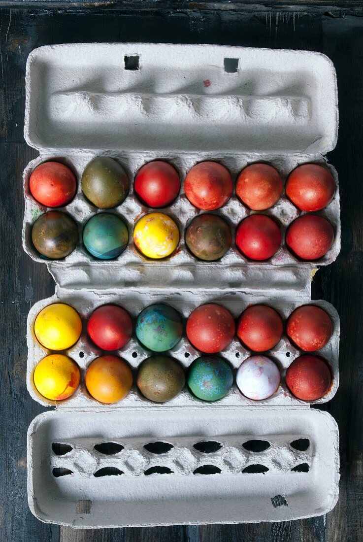 Naturally dyed eggs in an egg box for Easter