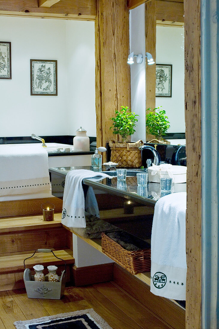Doppelwaschtisch aus schwarzem Marmor, Holzstufen vor Badewanne in Chalet-Badezimmer