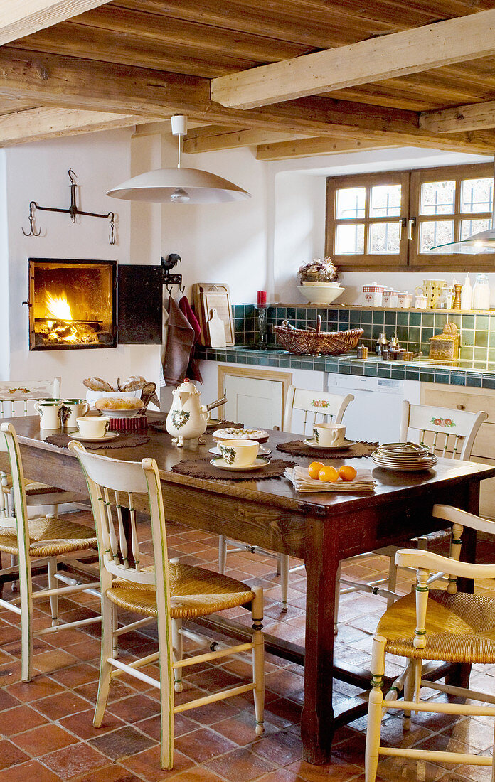 Holztisch mit Stühlen in der Küche mit offenem Holzofen