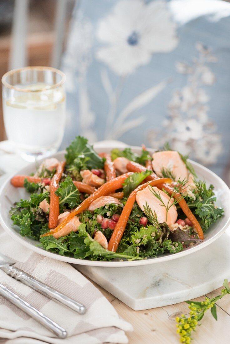 Fillet of salmon on a bed of baby Swiss chard with rice, glazed carrots and pomegranate seeds