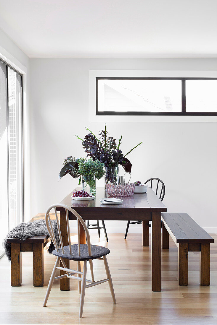 Dining table with benches and chairs in front of a patio door in an open living room