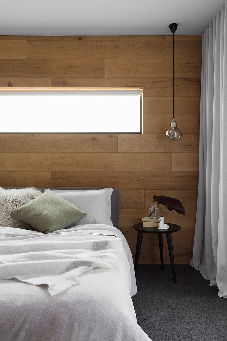 Double bed in the bedroom with wall made of recycled oak