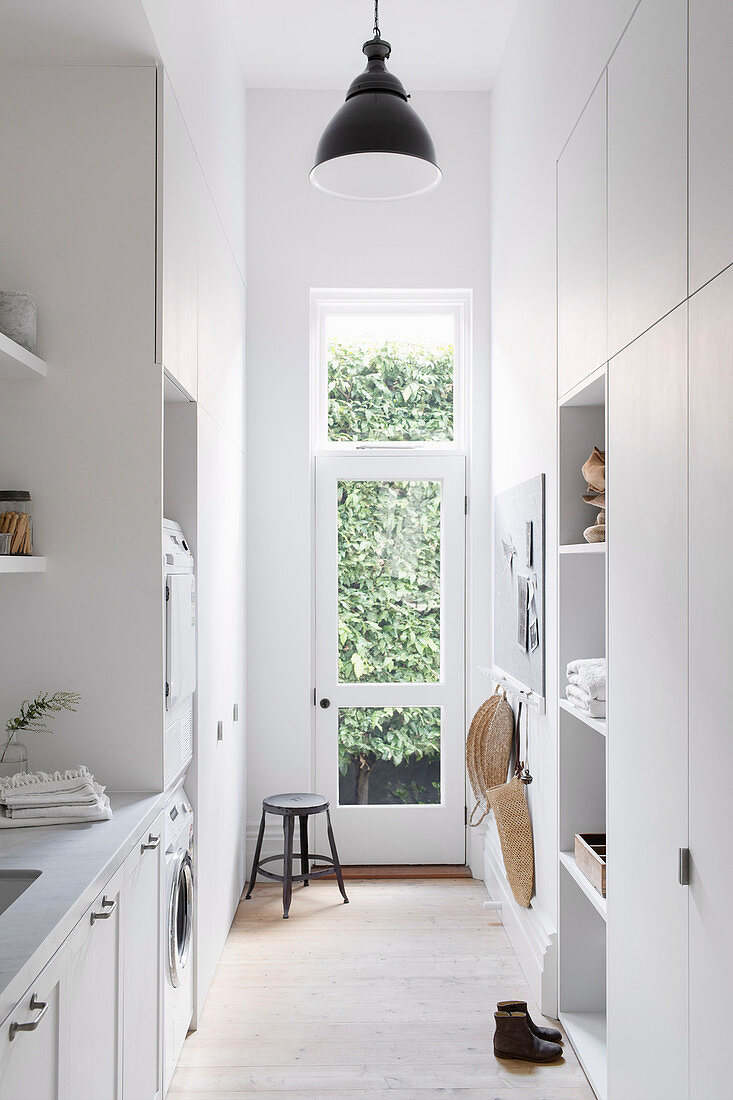 Laundry room all in white with fitted wardrobes and garden door