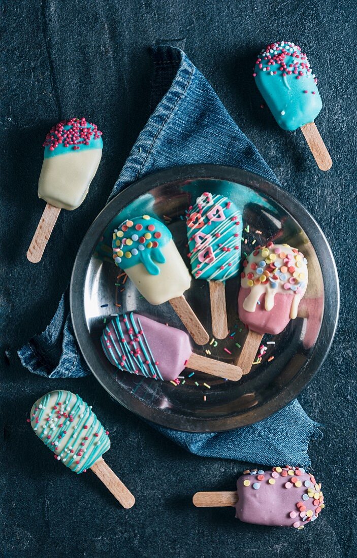 Cake pops in the shape of ice lollies with brightly coloured icing (seen from above)