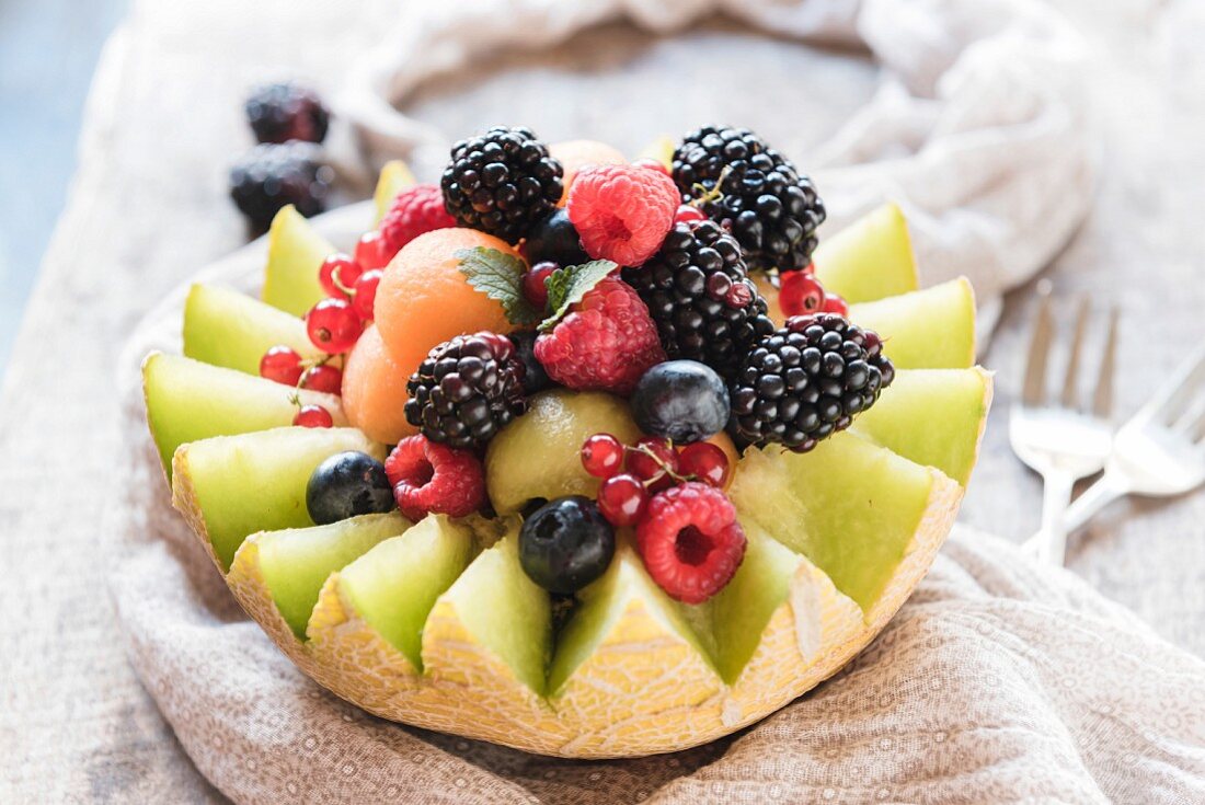 A halved melon filled with melon balls and fresh berries