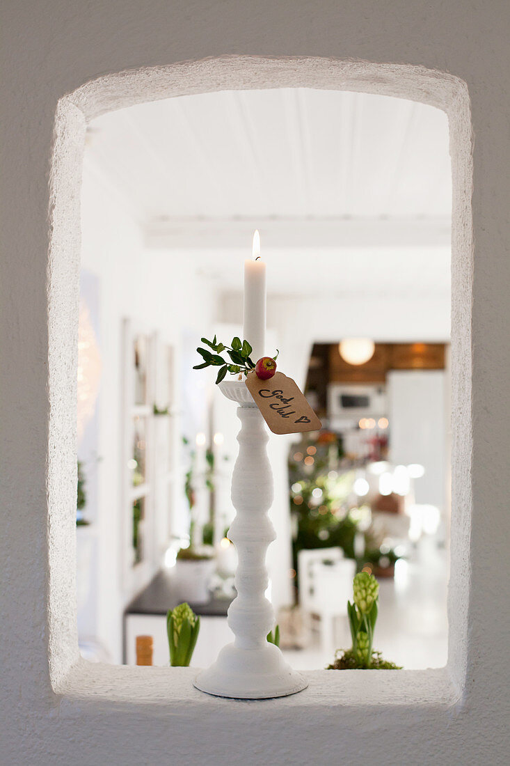 Lit candles and Christmas greetings in aperture in wall