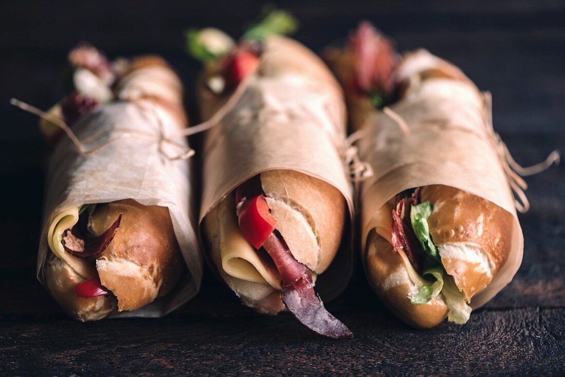 Three submarine sandwiches on wooden background