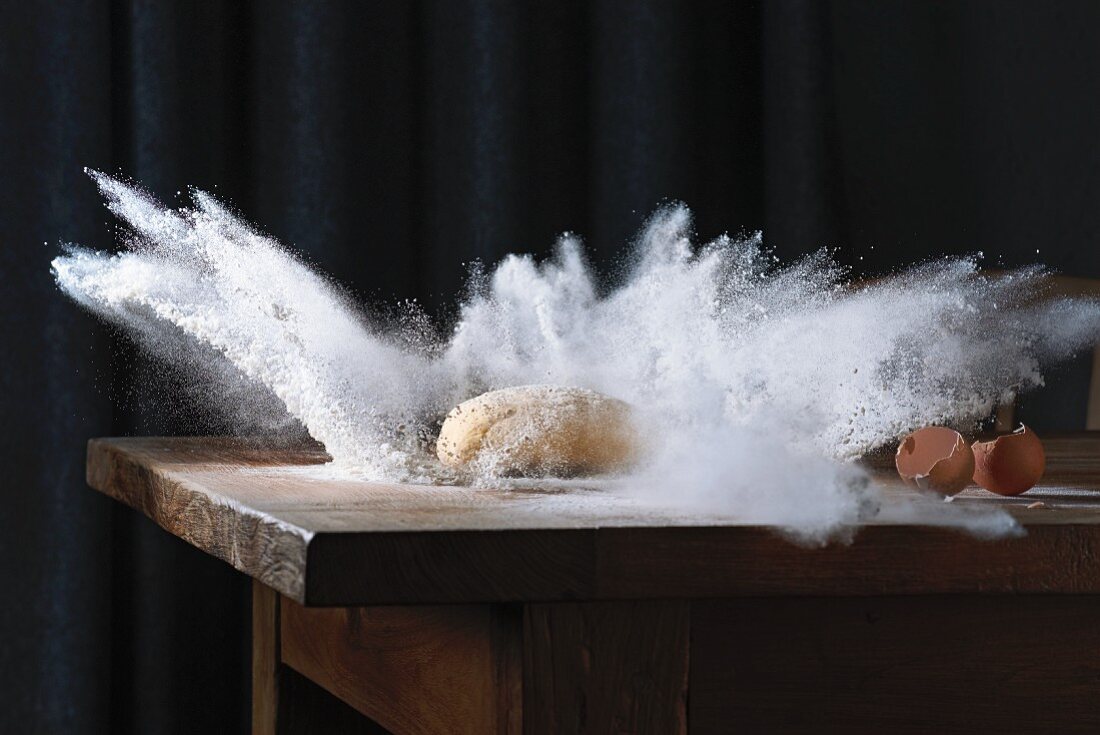 A ball of dough falling onto a floured surface