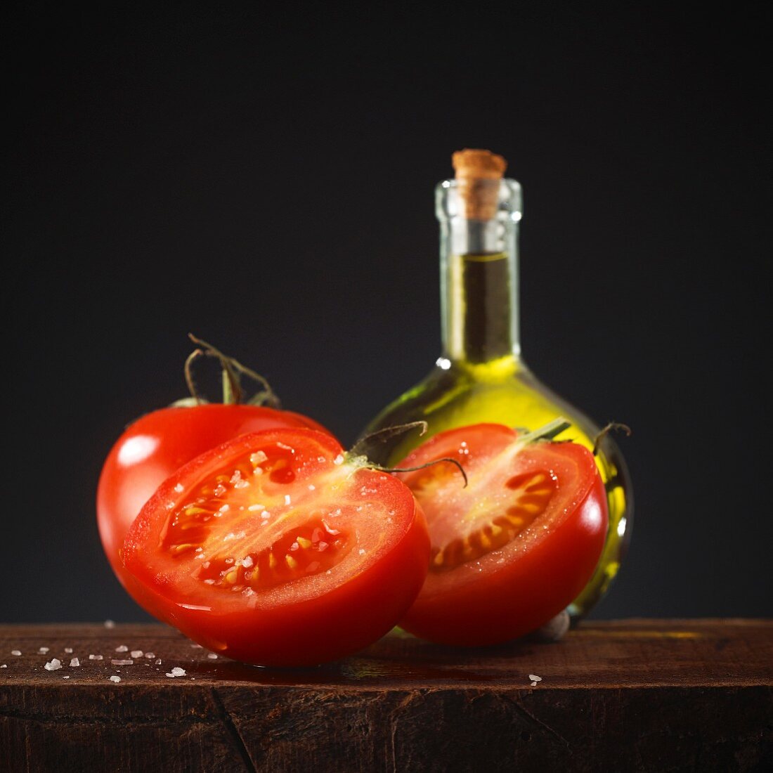 Fresh tomatoes in front of a bottle of olive oil