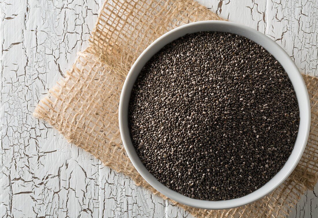 Black chia seeds in a bowl on a rustic wooden table