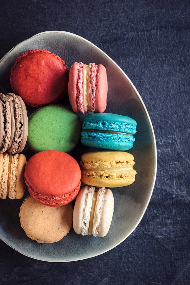 Sweet and colorful macaroon cookies in the plate on dark background