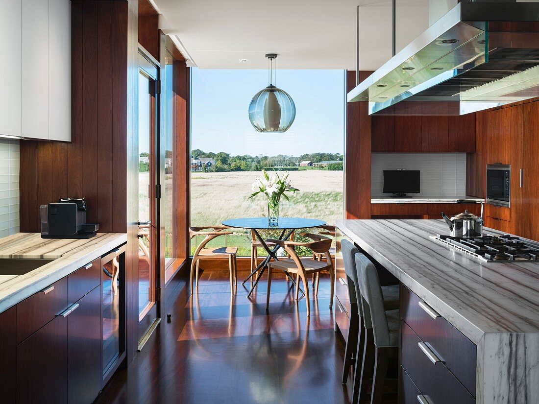Dining area in front of window in modern kitchen with wooden and marble elements