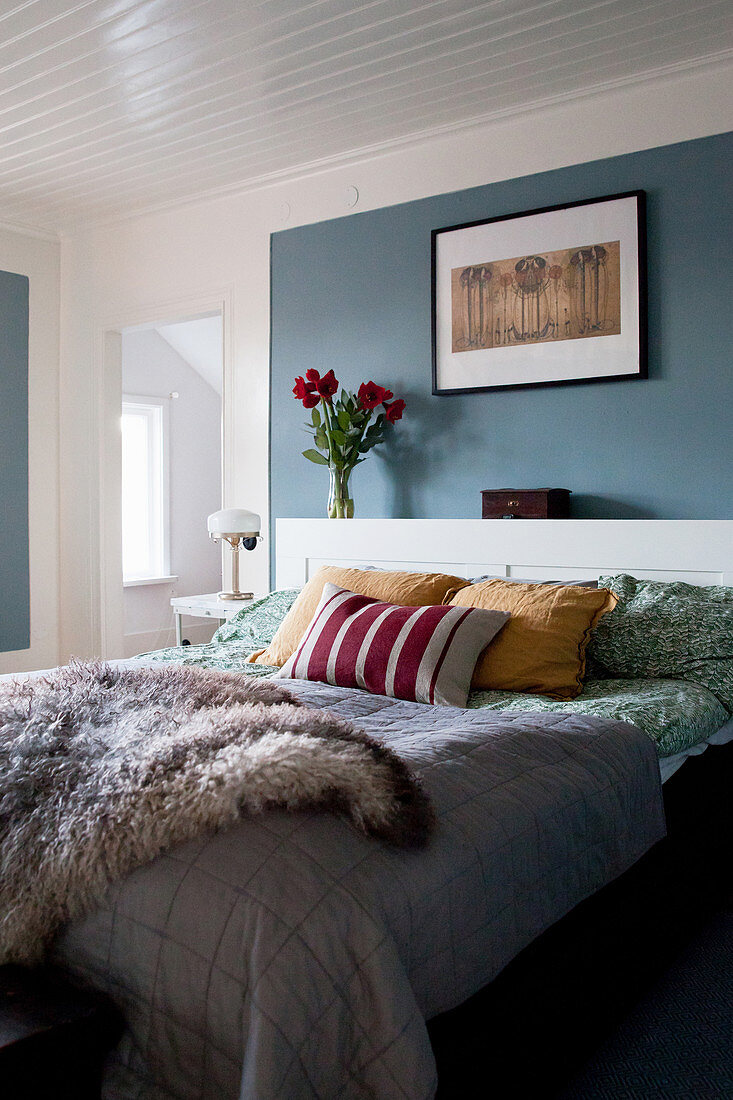 Fell auf dem Bett vor blauer Wand im Schlafzimmer