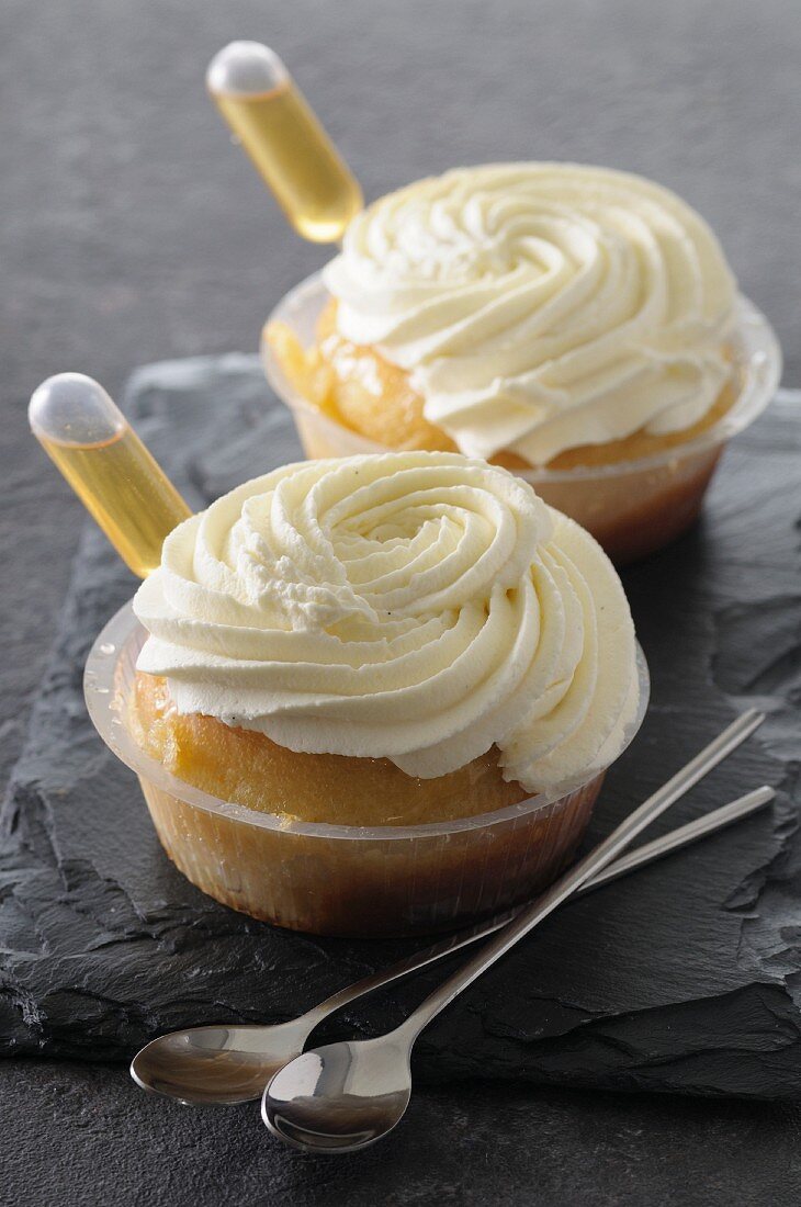 Rum baba with cream in plastic bowls