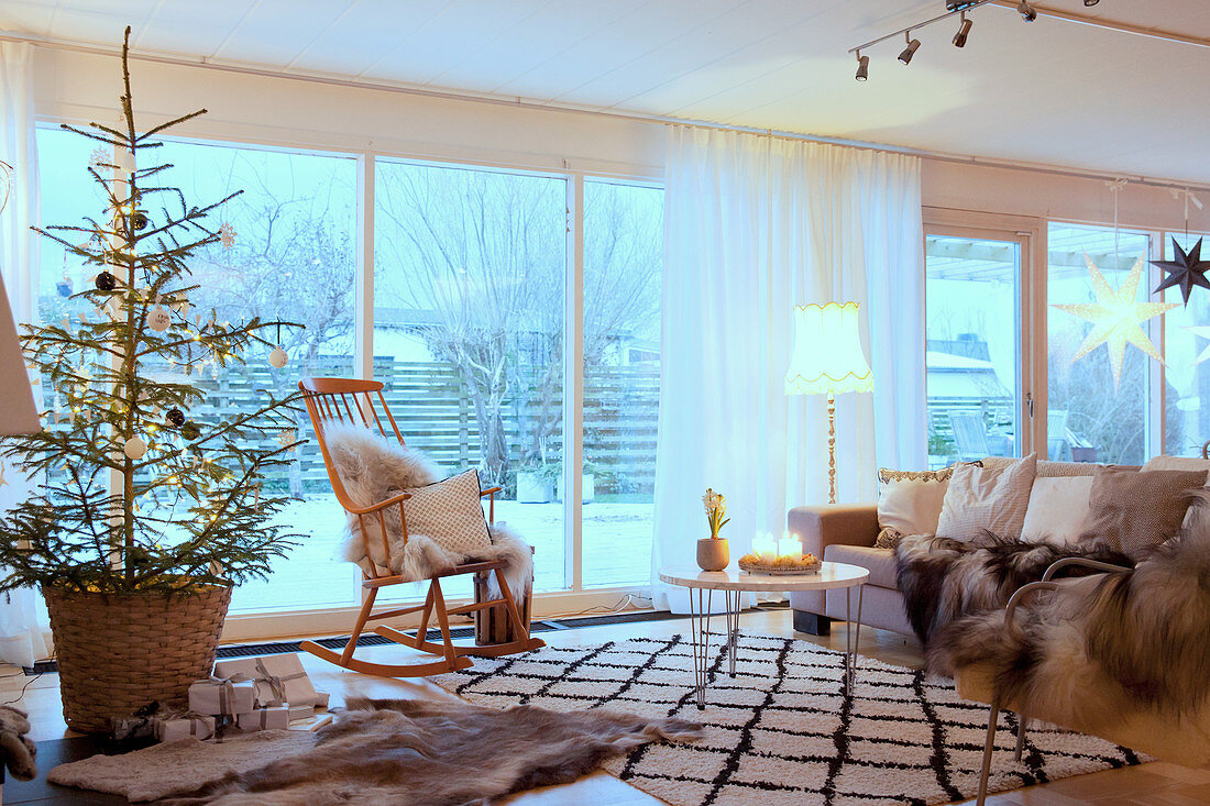 Rocking chair and Christmas tree in cosy living room with glass wall