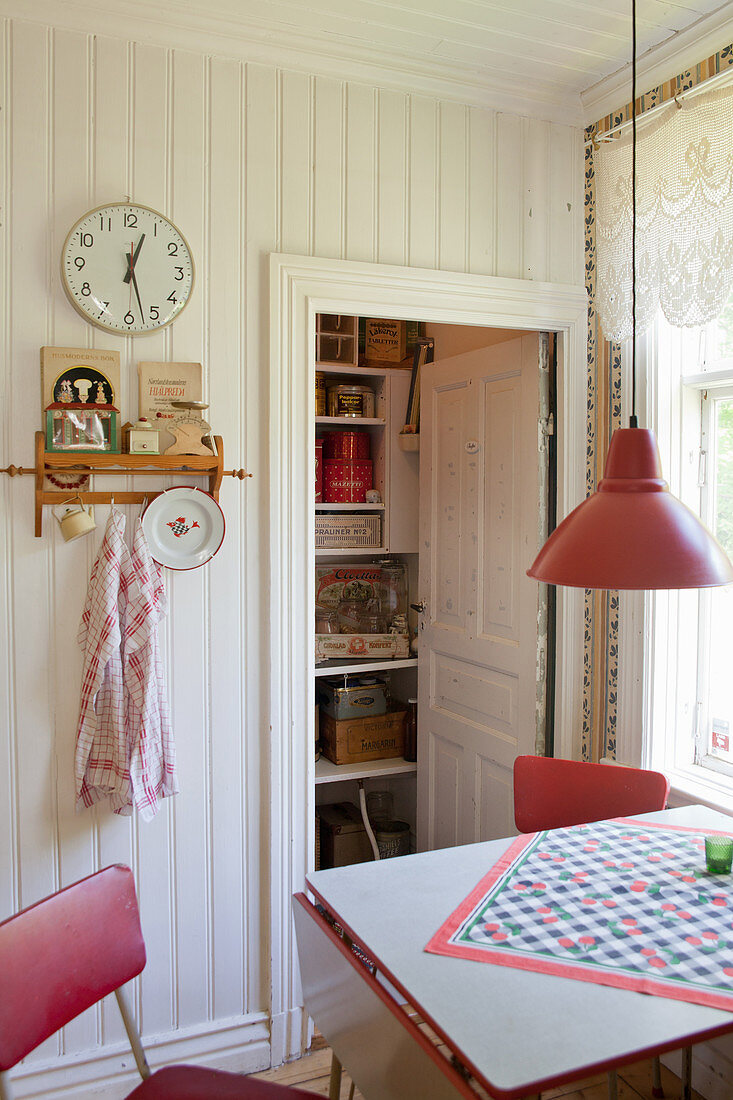 Kitchen table and red chairs in front of open pantry door