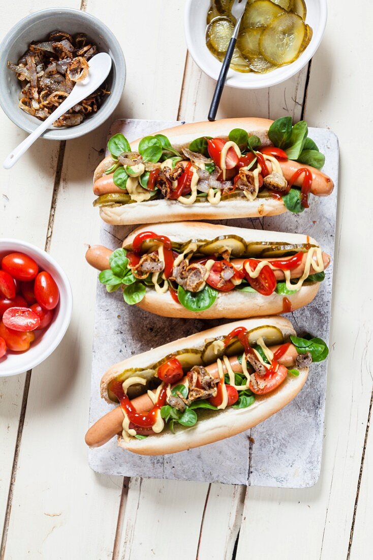 Hot Dogs mit Salat, Tomaten, Gurken, Ketchup, Senf und Röstzwiebeln