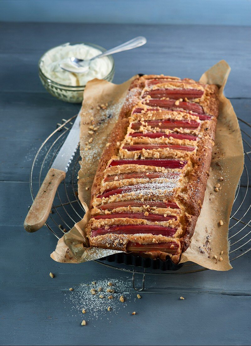 Rhubarb cake with marzipan, wrapped in baking paper, on a cooling rack