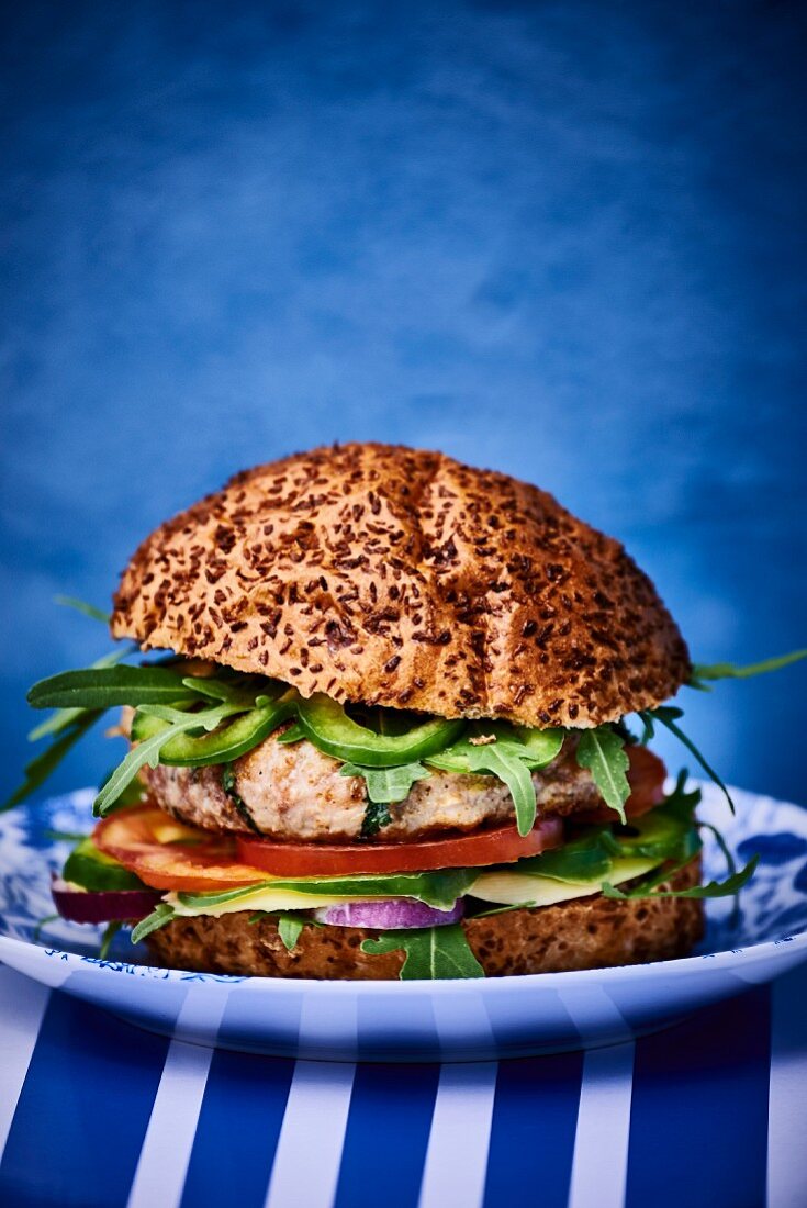 A chicken burger with avocado and rocket