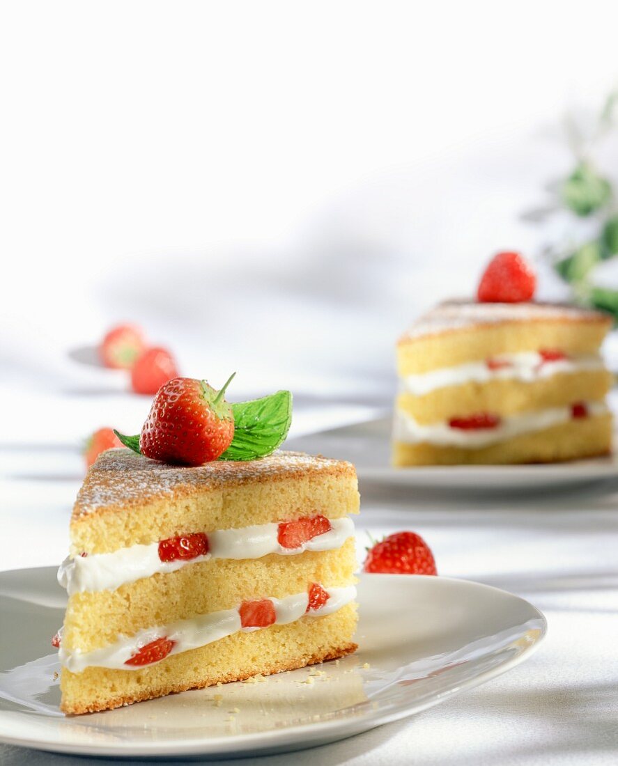 Two pieces of strawberry cake with whipped cream