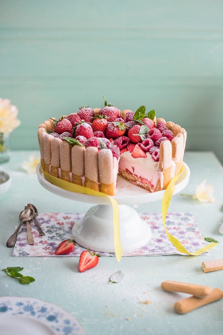 Raspberry and strawberry charlotte on a cake stand, slice removed