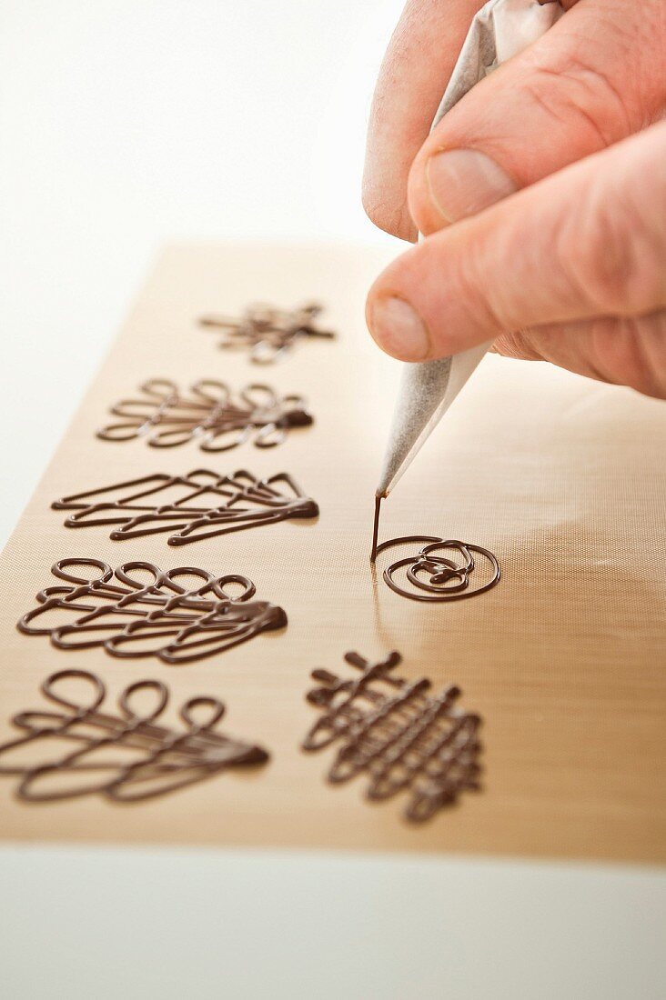 Piping chocolate decorations on baking paper
