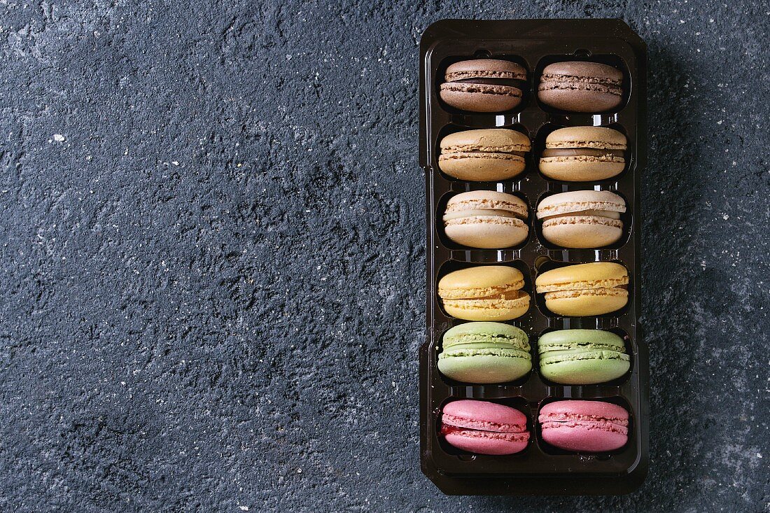 Bunte französische Macarons mit verschiedenen Füllungen in Kunststoffbox