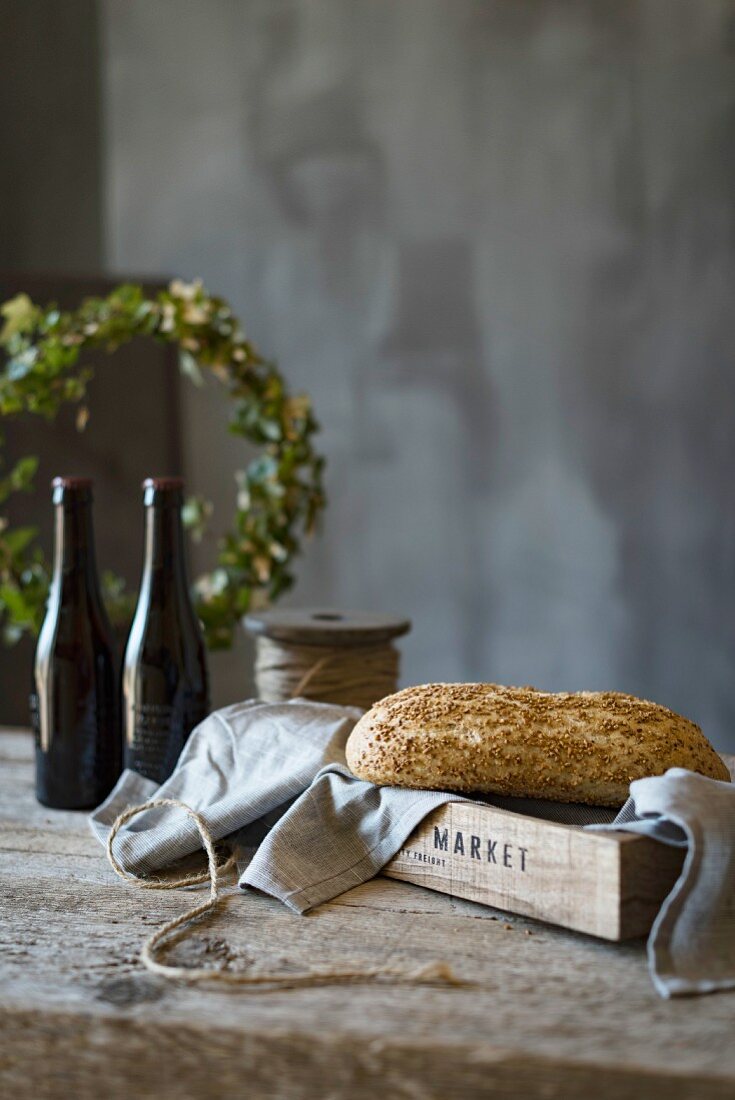 Ein Laib Brot mit Leinentuch auf Holztablett und rustikalem Holztisch