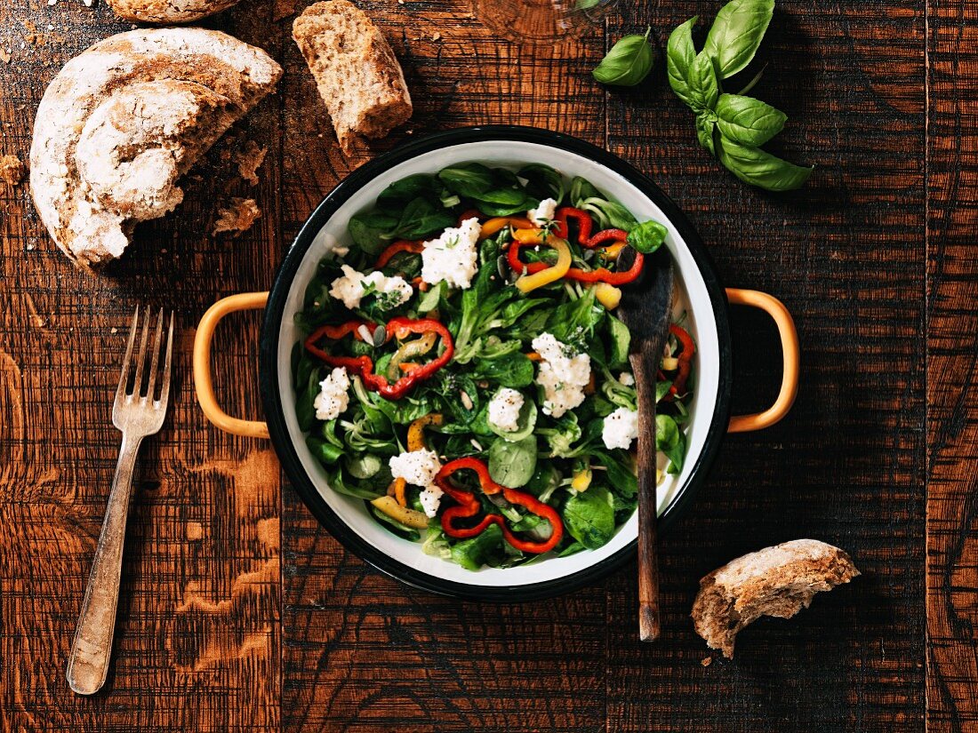 Feldsalat mit Ricotta und Paprika serviert mit Brot (Aufsicht)