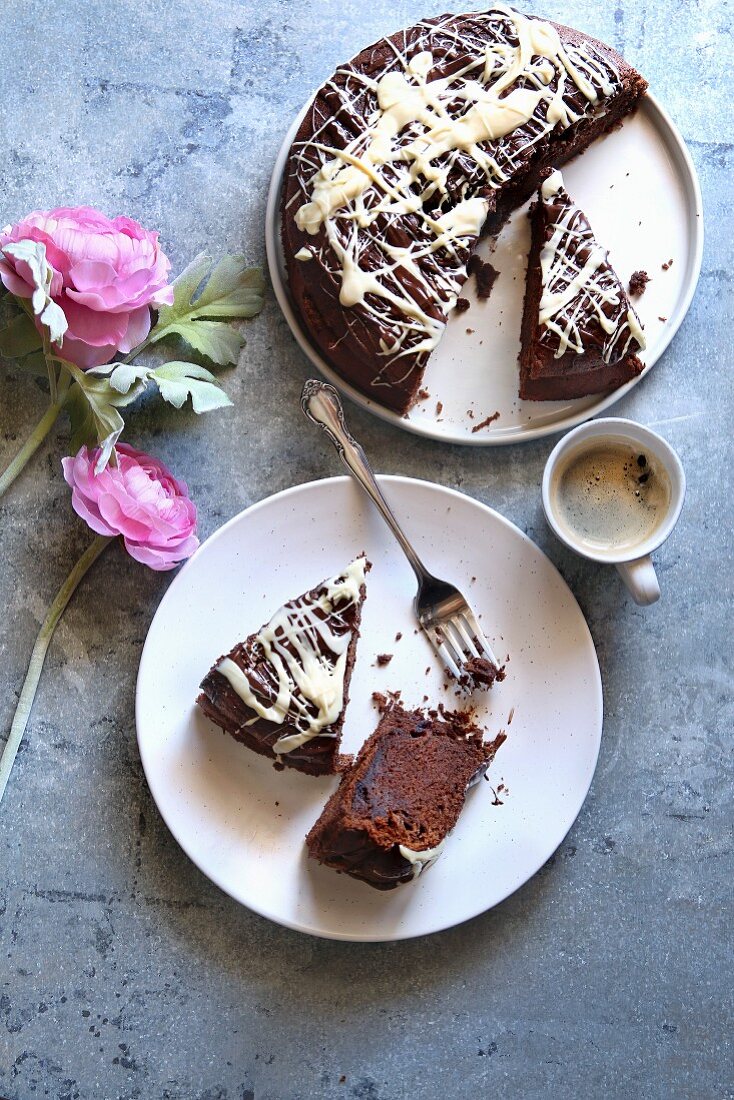 Slices of chocolate cake on a plate, a cup o coffee and flowers on the table