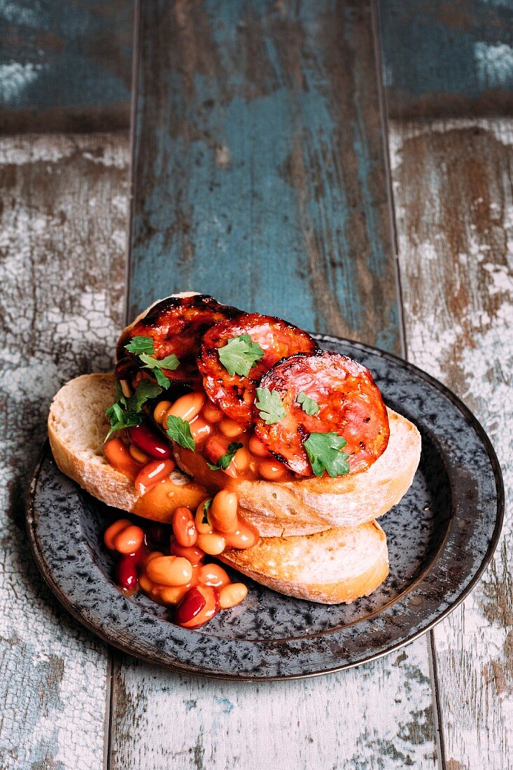 Breakfast with mixed beans, sourdough toast chorizo, garlic and flat leaf parsley