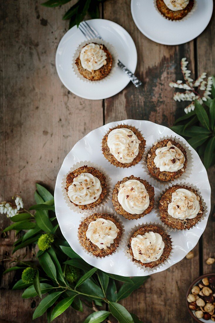 Karotten-Kokos-Cupcakes auf Kuchenständer und Tellern (Aufsicht)