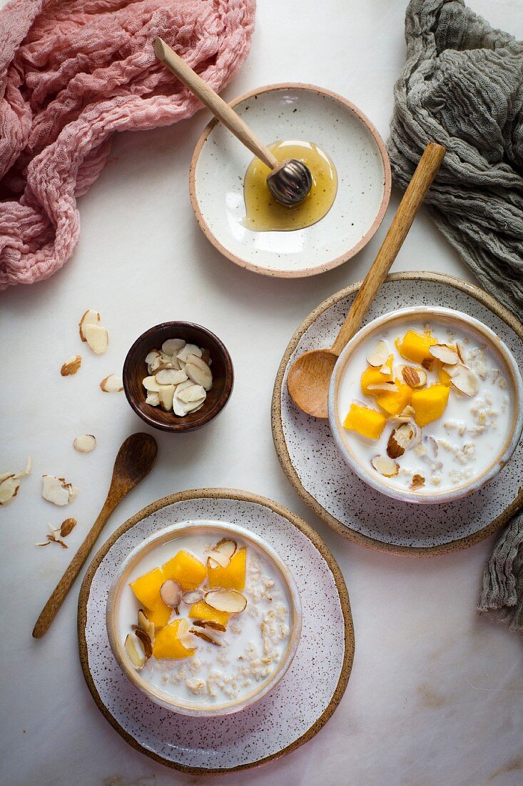 Haferflockenbrei mit Milch, Mango, Honig und Mandeln (Aufsicht)