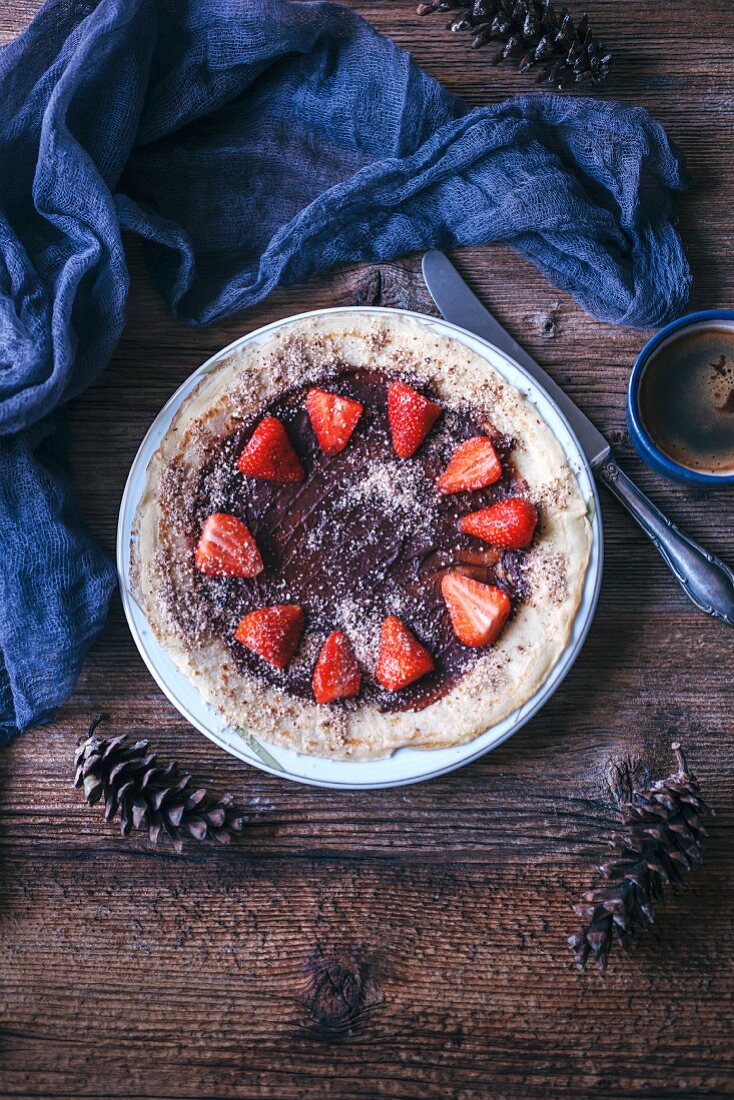 A crêpe with chocolate spread, fresh strawberries and ground almonds