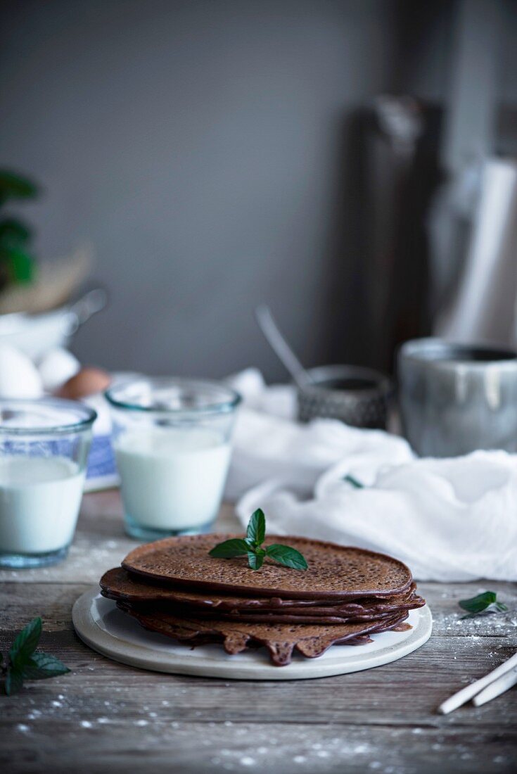 Chocolate pancakes on a plate with the ingredients in the background