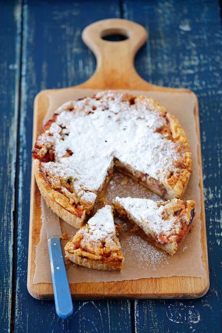 Rhabarber-Erdbeer-Kuchen, angeschnitten auf Holzbrett