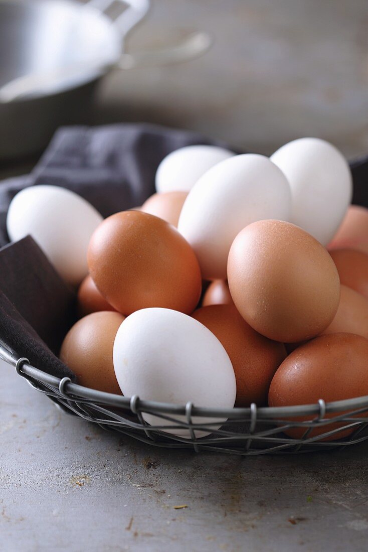 Brown and white chicken eggs in a wire basket